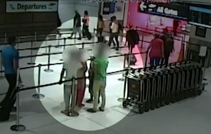 CCTV image of people at an airport. Faces are blurred